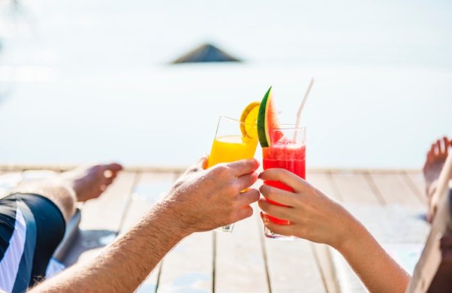 Couple drinking cocktails - 6 Money-Saving Tips for Planning Your Honeymoon